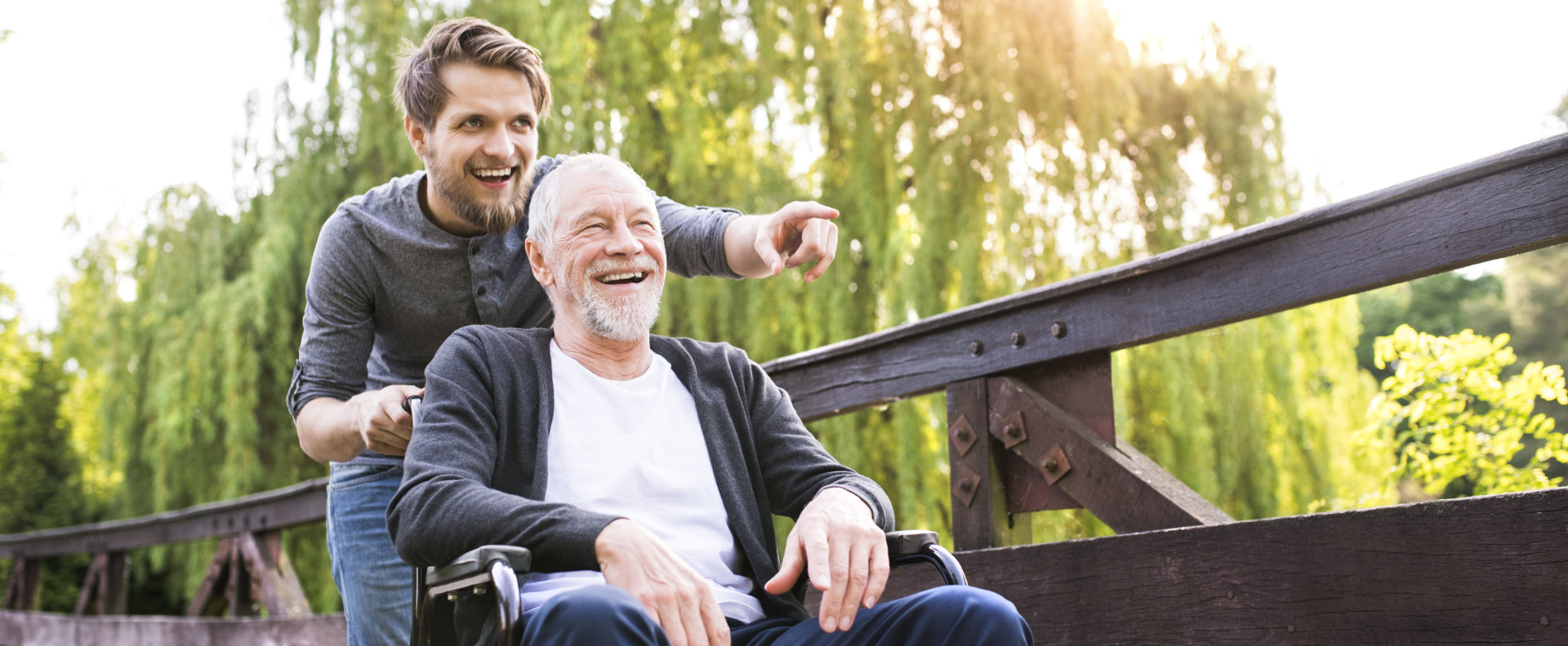 man walking with disabled elderly in wheelchair at park