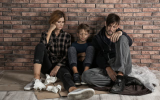 Poor homeless family sitting on floor