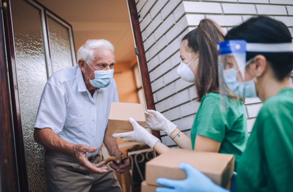 Young volunteers gives an elderly man boxes